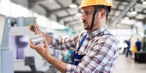Male worker and quality control inspection in metal industry factory