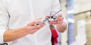 Young businessman in factory holding component